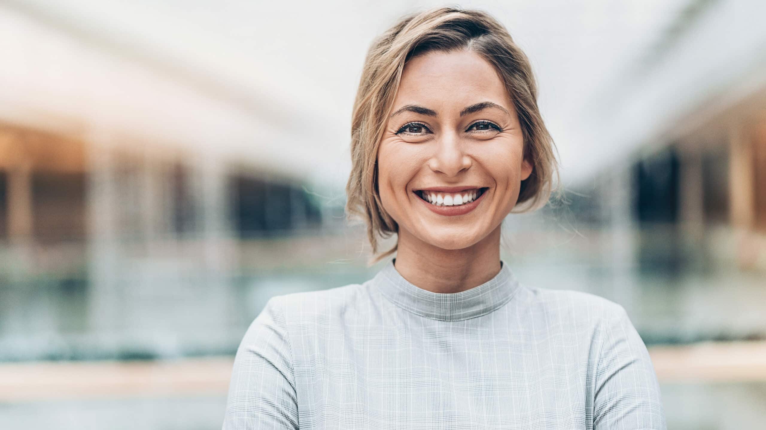 Lachende Frau. Diese ist zufrieden mit der Cyber Security Strategie ihres Krankenhauses.